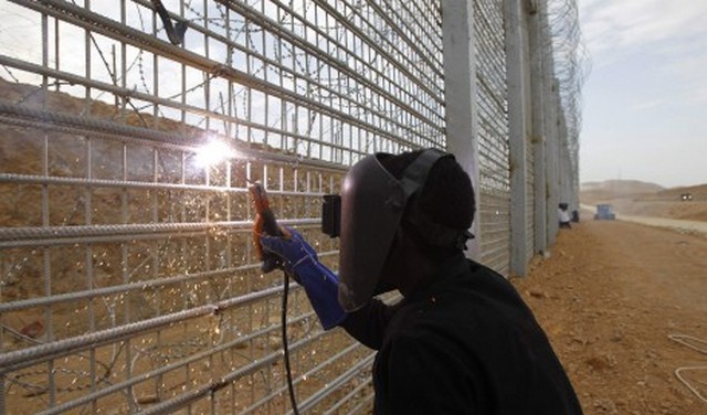 A migrant worker works on the construction of a barrier on the border between Israel and Egypt along Israel's Highway 12, a desert road north of the Red Sea resort of Eilat, in this February 15, 2012 file picture. With a rise of Islamist militant violence in Egypt's Sinai desert, Israel in 2011 began accelerating fortification of its porous southern border along Sinai with the five-metre(16-ft)-high fence, state-of-the art surveillance and special military forces, delivering a severe blow to drug smugglers. REUTERS/Baz Ratner/Files (ISRAEL - Tags: POLITICS SOCIETY IMMIGRATION)